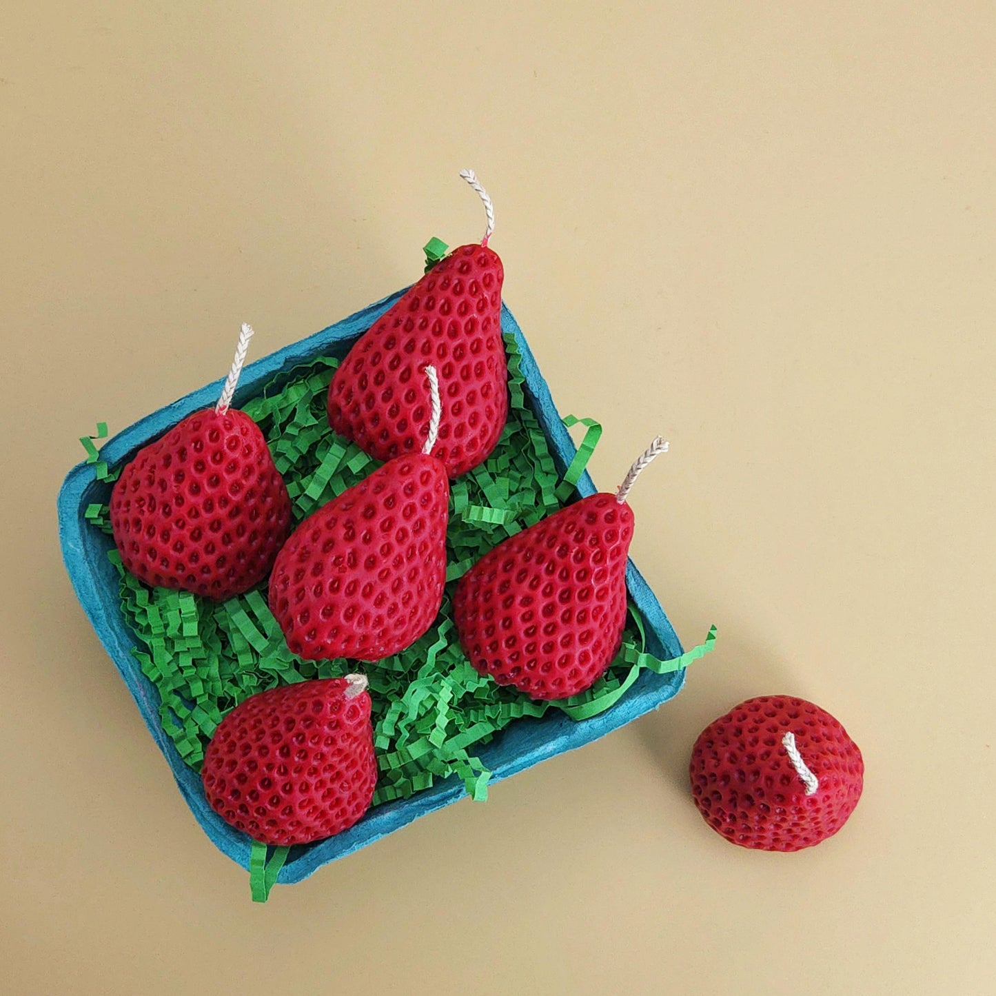A realistic basket of strawberry candles, strawberry set candle, blue pulp basket of strawberries, red strawberry with wick on yellow background, green crinkle cut paper inside, gift of cake topper, birthday strawberry topper, berry with holes, looks like real strawberry, birthday candles, home decor, kitchen decor candles, giving off a sweet strawberry scent, juicy strawberry, strawberry-shaped soy candles