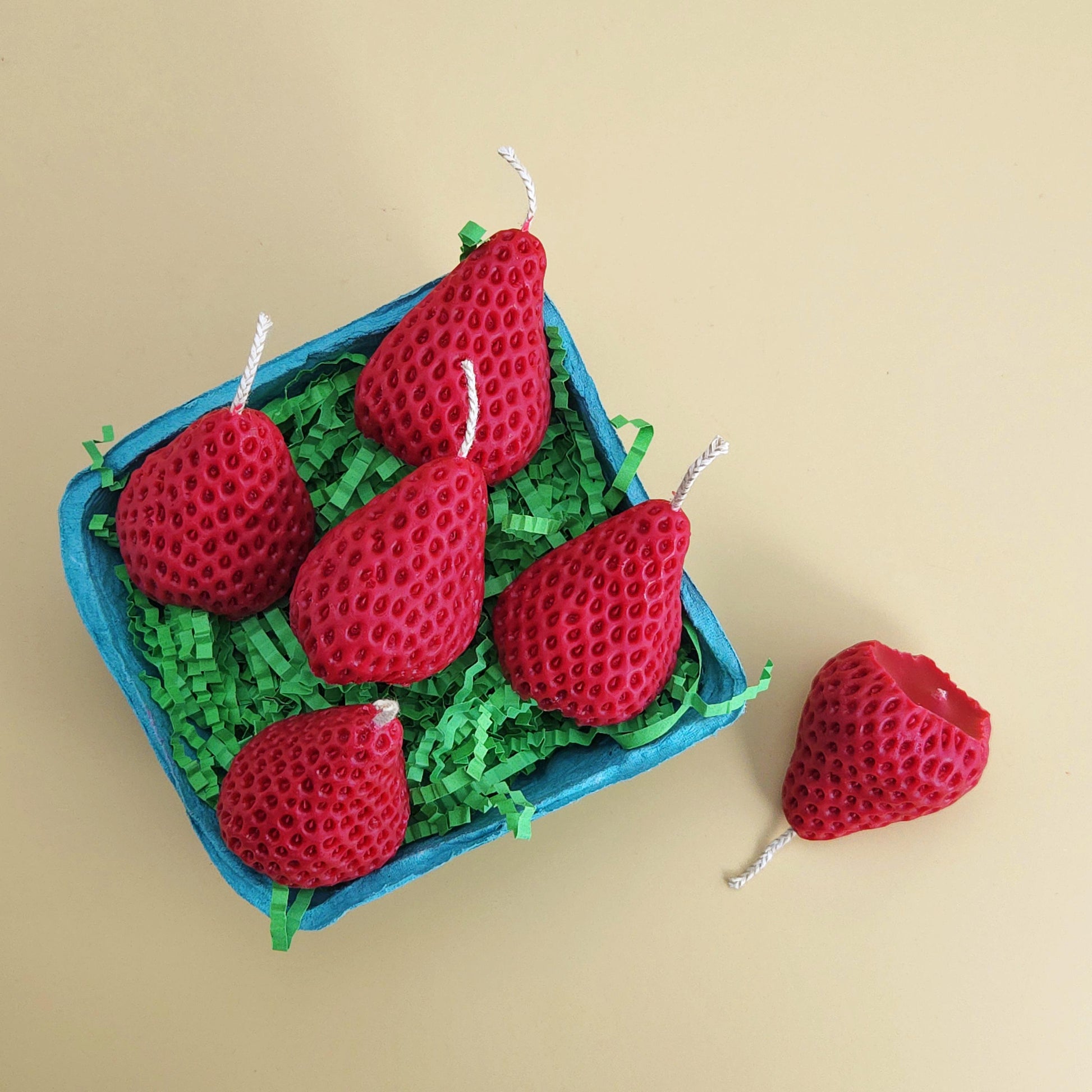 A realistic basket of strawberry candles, strawberry set candle, blue pulp basket of strawberries, red strawberry with wick on yellow background, green crinkle cut paper inside, gift of cake topper, birthday strawberry topper, berry with holes, looks like real strawberry, birthday candles, home decor, kitchen decor candles, giving off a sweet strawberry scent, juicy strawberry, strawberry-shaped soy candles