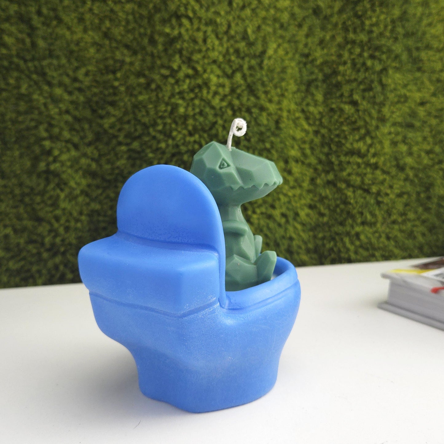 Handmade soy wax candle shaped like a green dinosaur sitting on a blue toilet, funny novelty gag gift