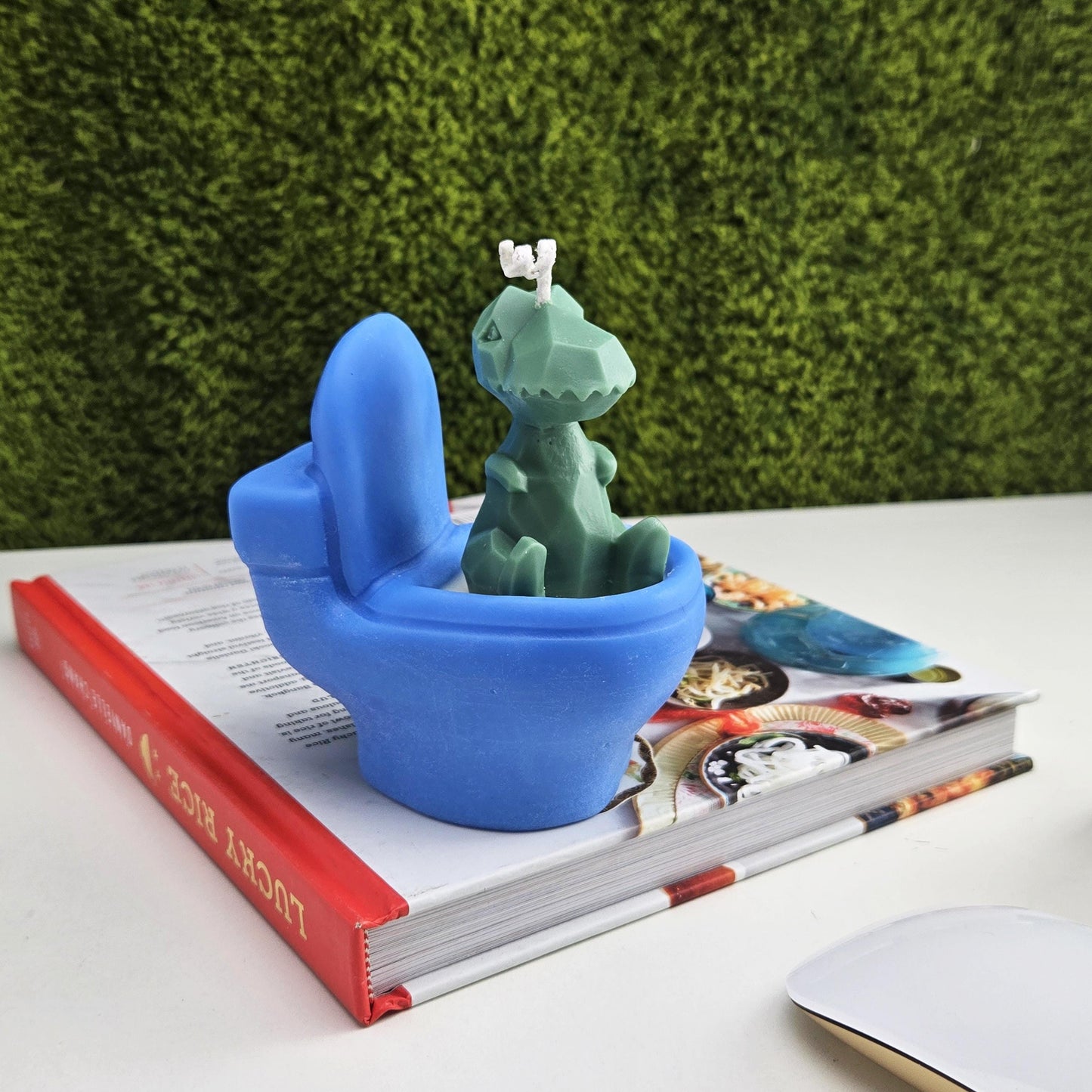 Handmade soy wax candle shaped like a green dinosaur sitting on a blue toilet, funny novelty gag gift