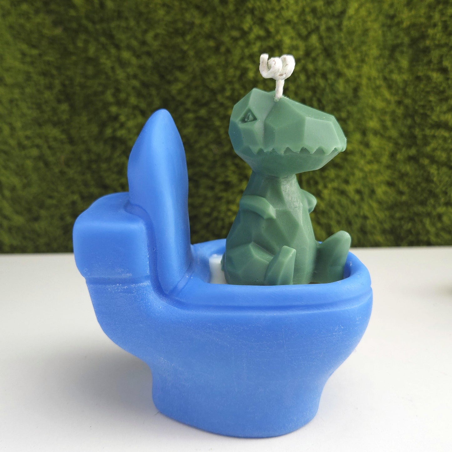 Handmade soy wax candle shaped like a green dinosaur sitting on a blue toilet, funny novelty gag gift