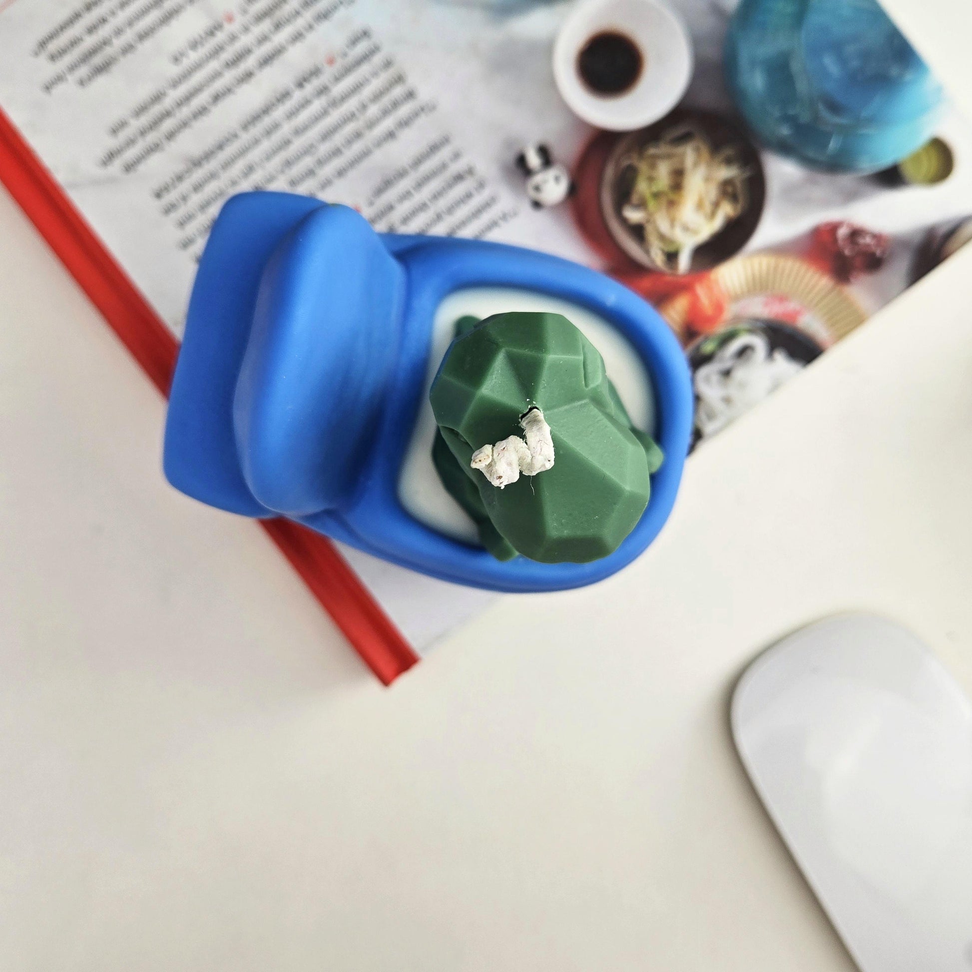 Handmade soy wax candle shaped like a green dinosaur sitting on a blue toilet, funny novelty gag gift