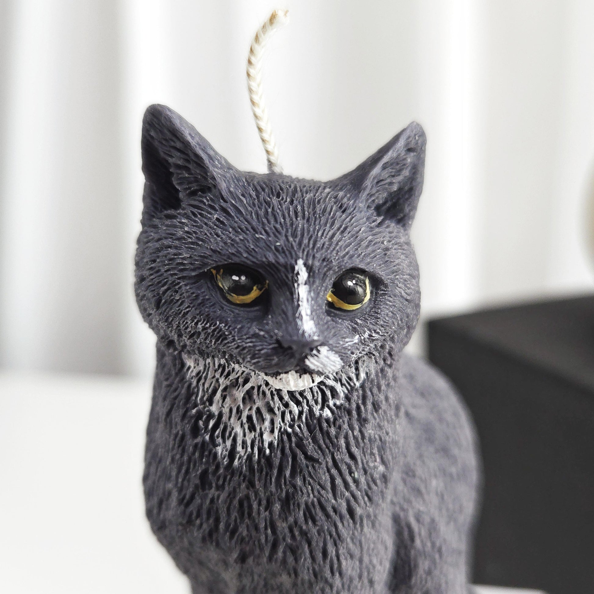 Close-up of black cat candle face with expressive eyes and smooth wax finish