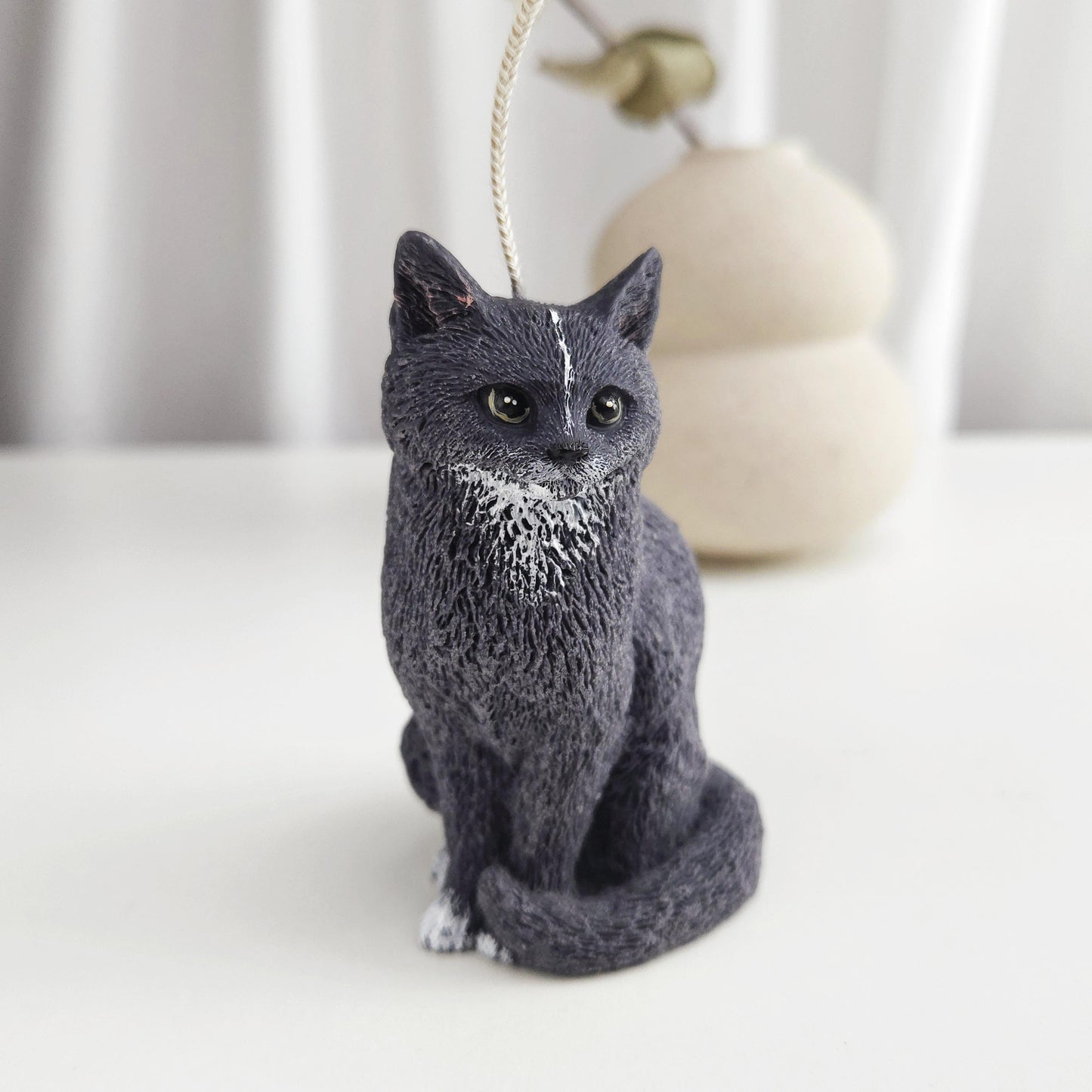 Handmade black cat figurine candle sitting upright with white chest detail on a neutral background