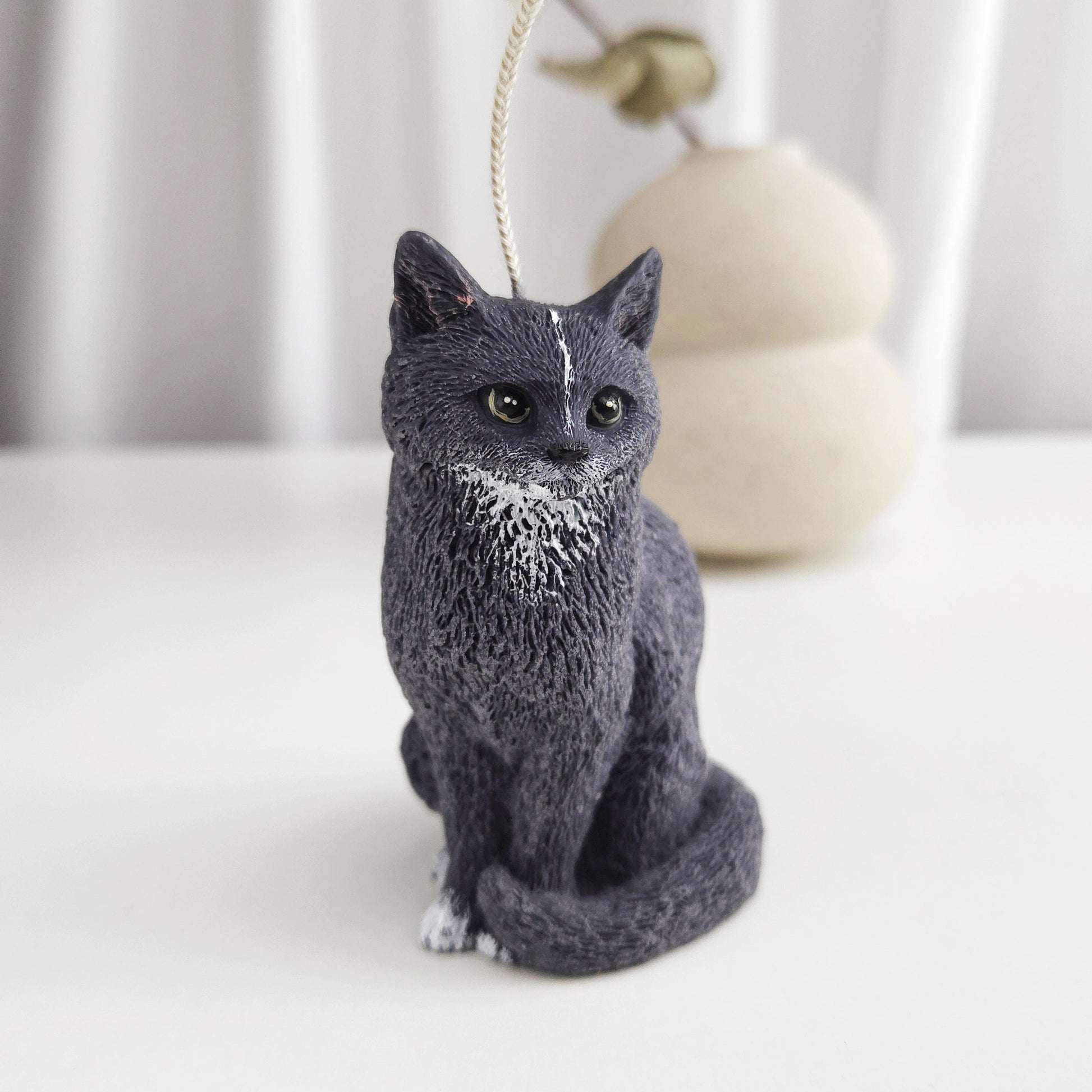 Handmade black cat figurine candle sitting upright with white chest detail on a neutral background